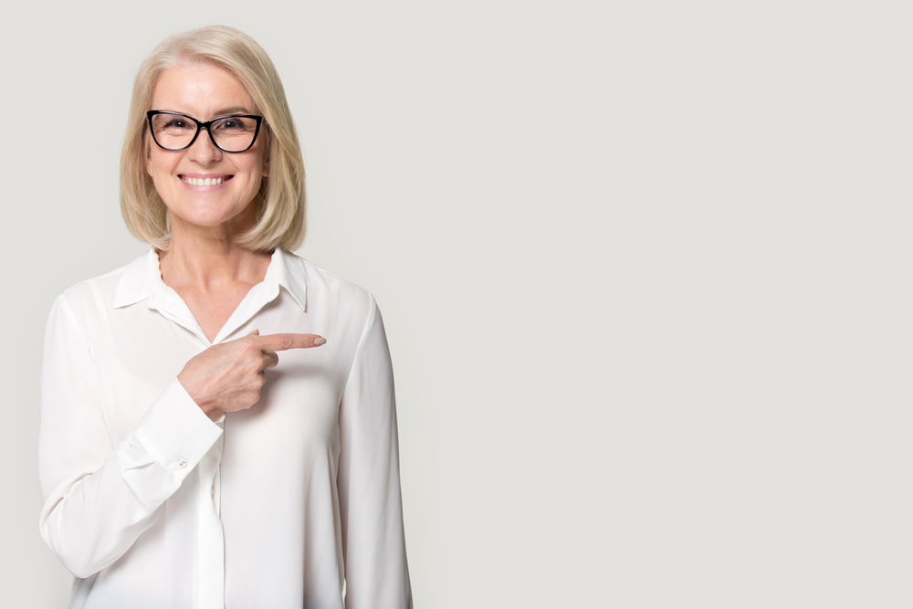 Older woman with glasses pointing.