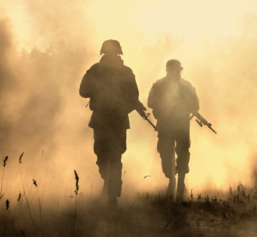 Military personnel in the field carrying guns.