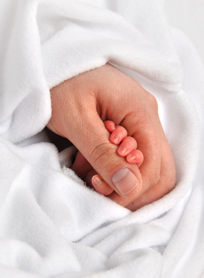 Mother holding baby’s hand after childbirth.