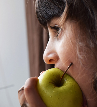 Little girl eating an apple.