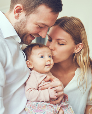 A mom and dad holding a healthy baby.