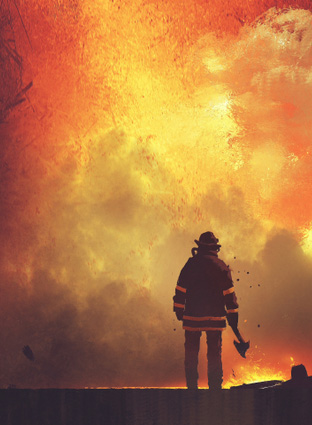 A firefighter with an ax approaching a fire.