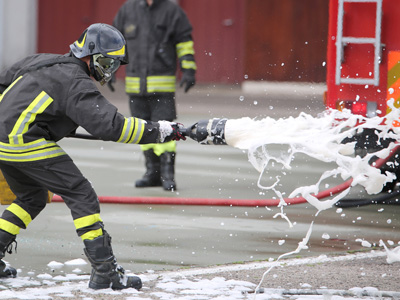 A firefighter using AFFF firefighting foam during training.